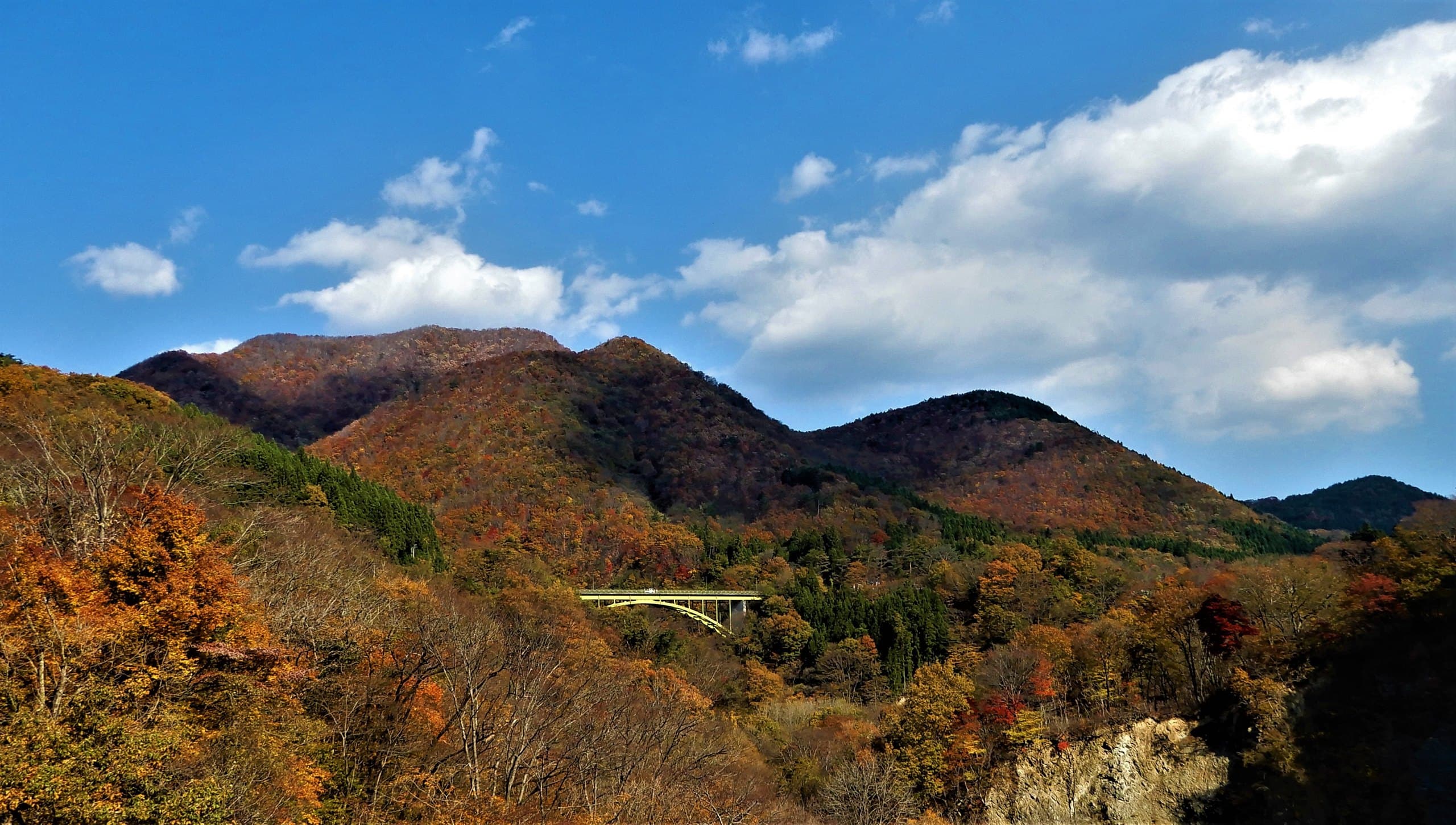 Wooded hills in autumn colour around Akiu, with a road bridge crossing the valley
