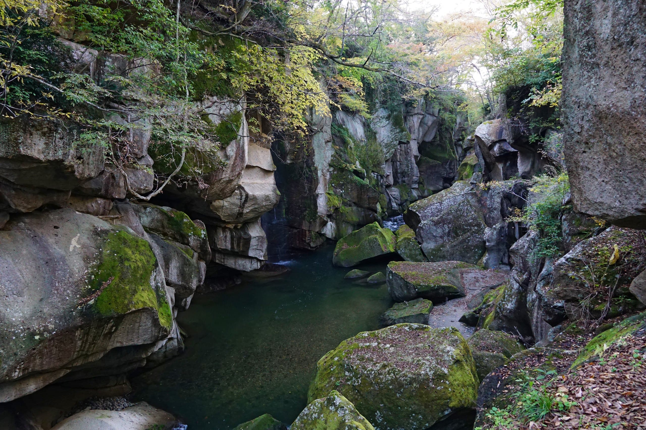 Mossy boulders and a still green pool between the rock walls of Rairaikyo gorge