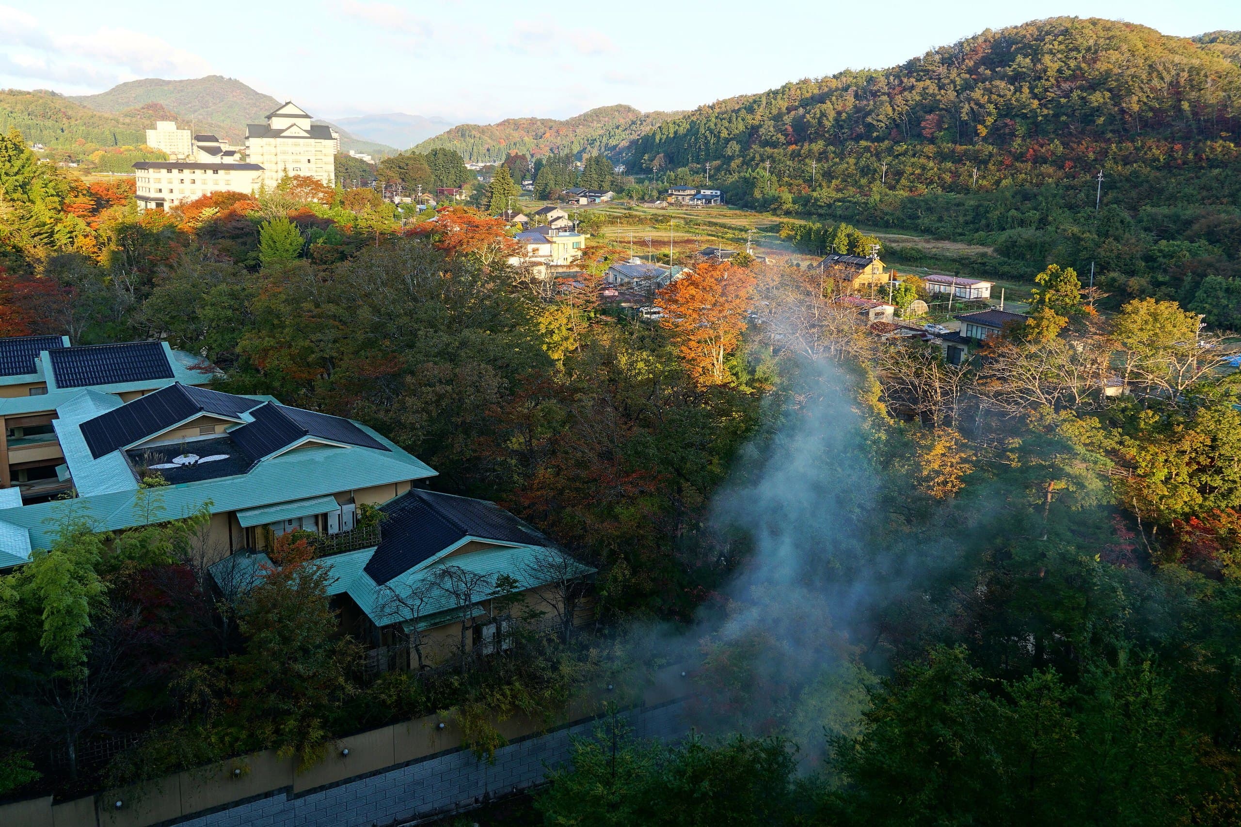 Hot spring steam rising from the wooded Akiu Onsen valley in autumn
