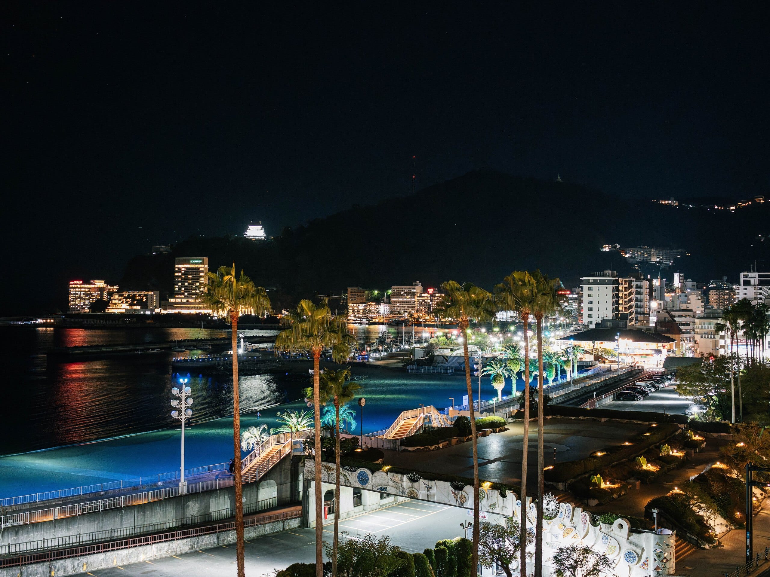 Atami seafront and bay lit up at night below the hills