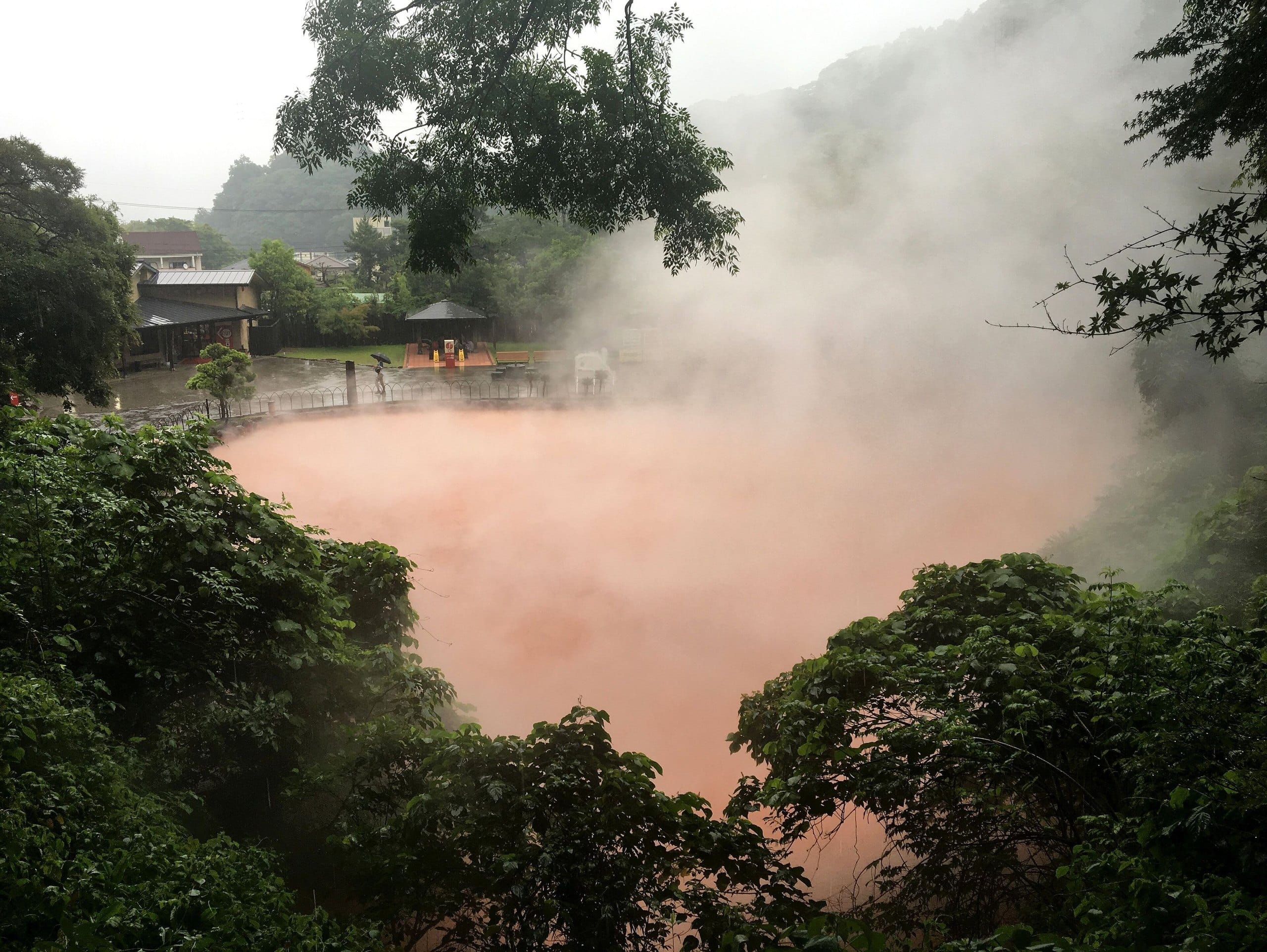 Steam hanging over the red waters of Chinoike Jigoku during heavy rain