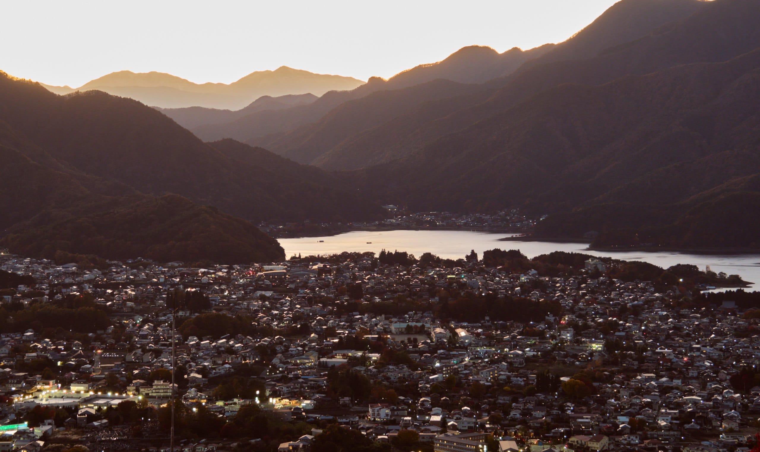 Kawaguchiko town and lake at dusk, ringed by layered mountain ridges