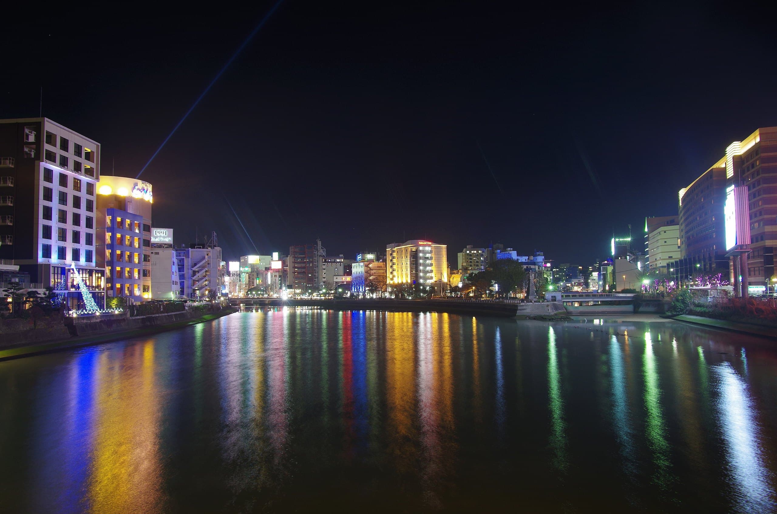 Fukuoka's riverside skyline at night with colourful light reflections