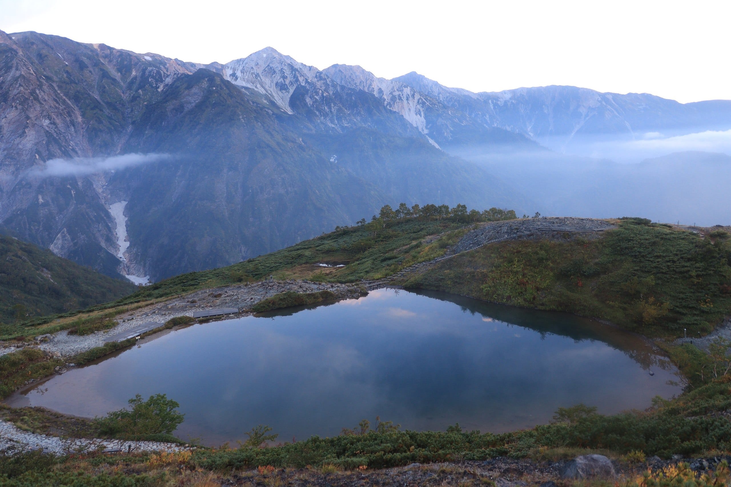 Happo Pond reflecting the Shirouma mountains under morning mist