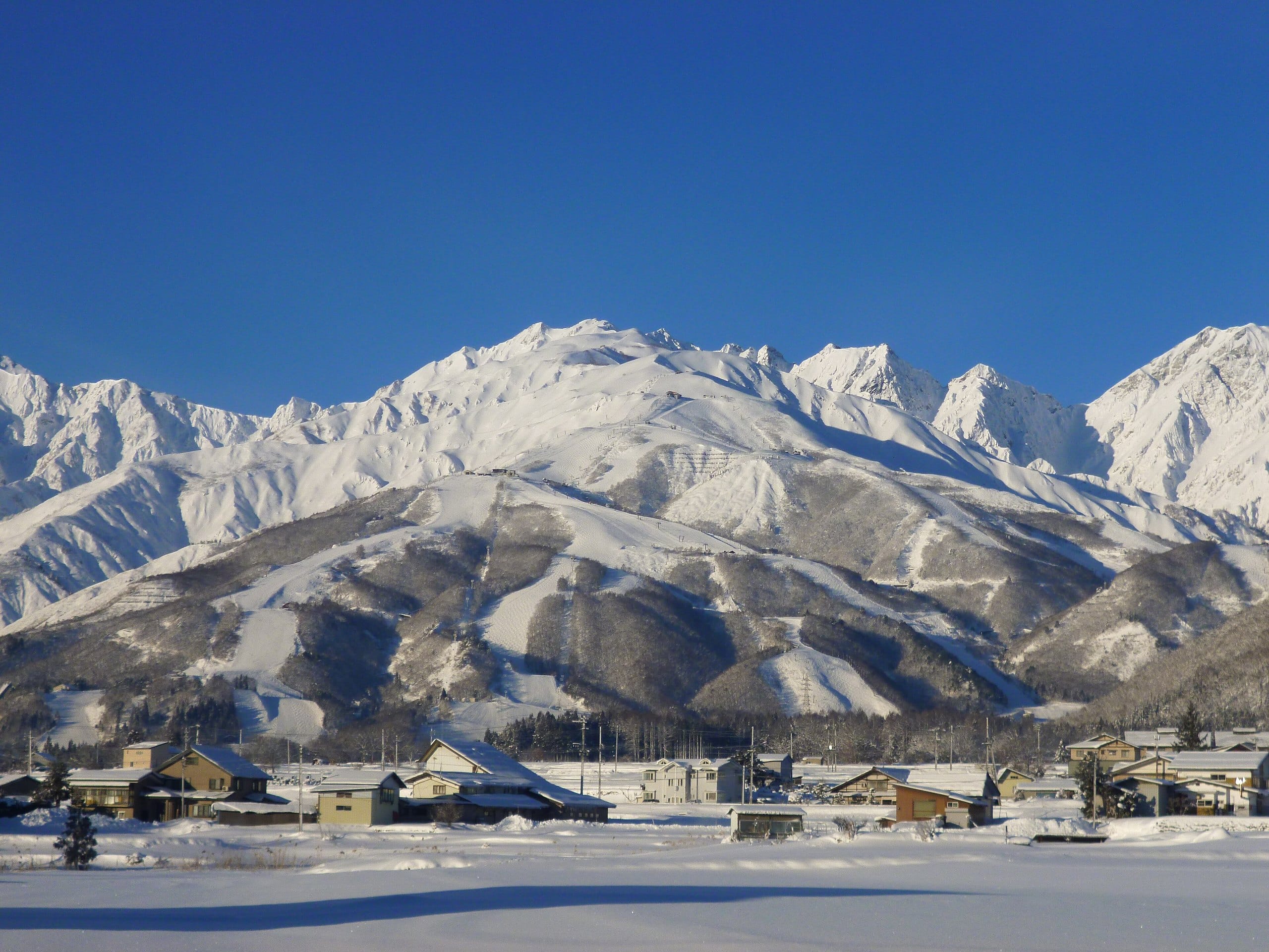 Snow-covered Hakuba village and fields below the white Northern Alps
