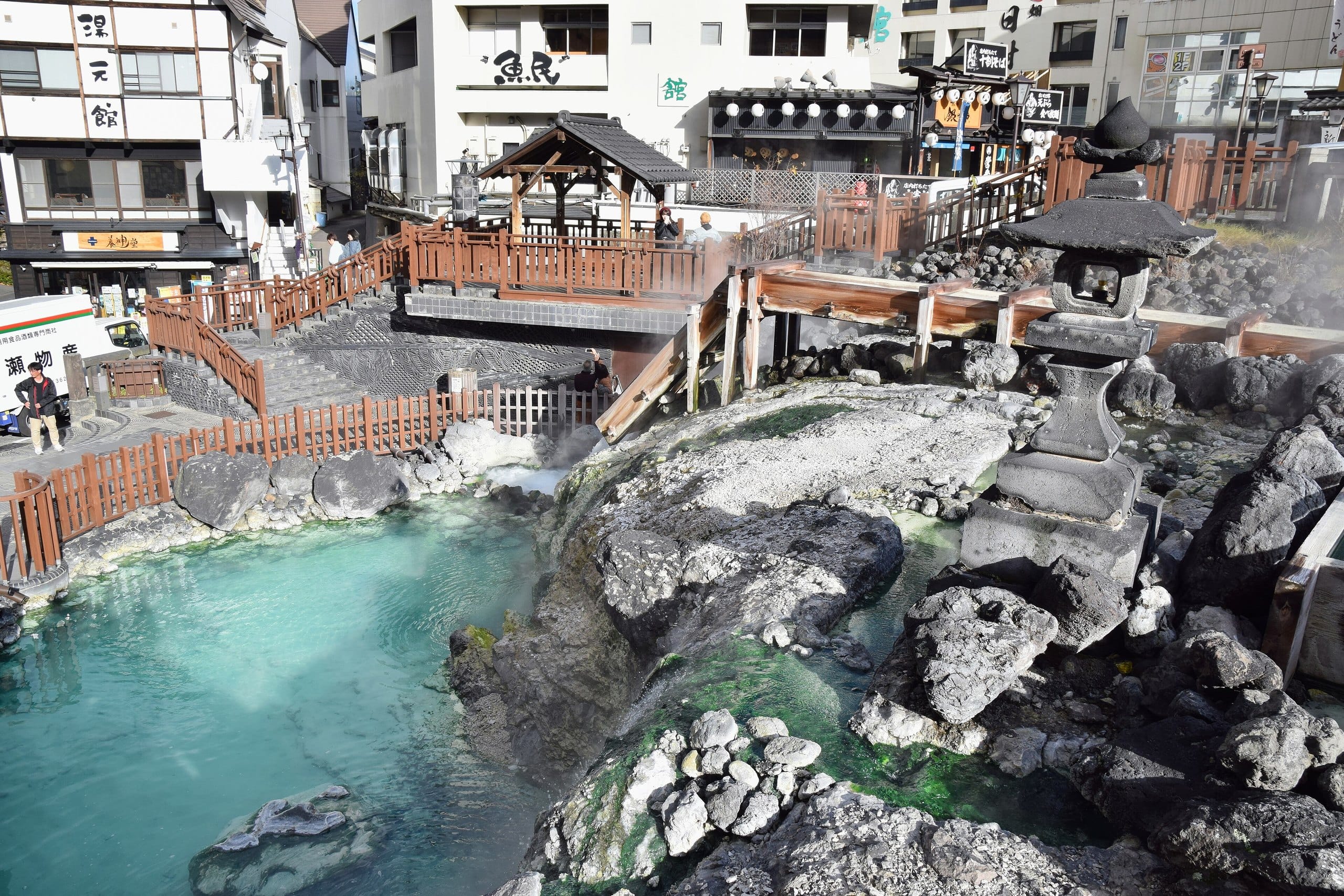 Turquoise spring water and mineral-crusted rocks at the source of the Yubatake