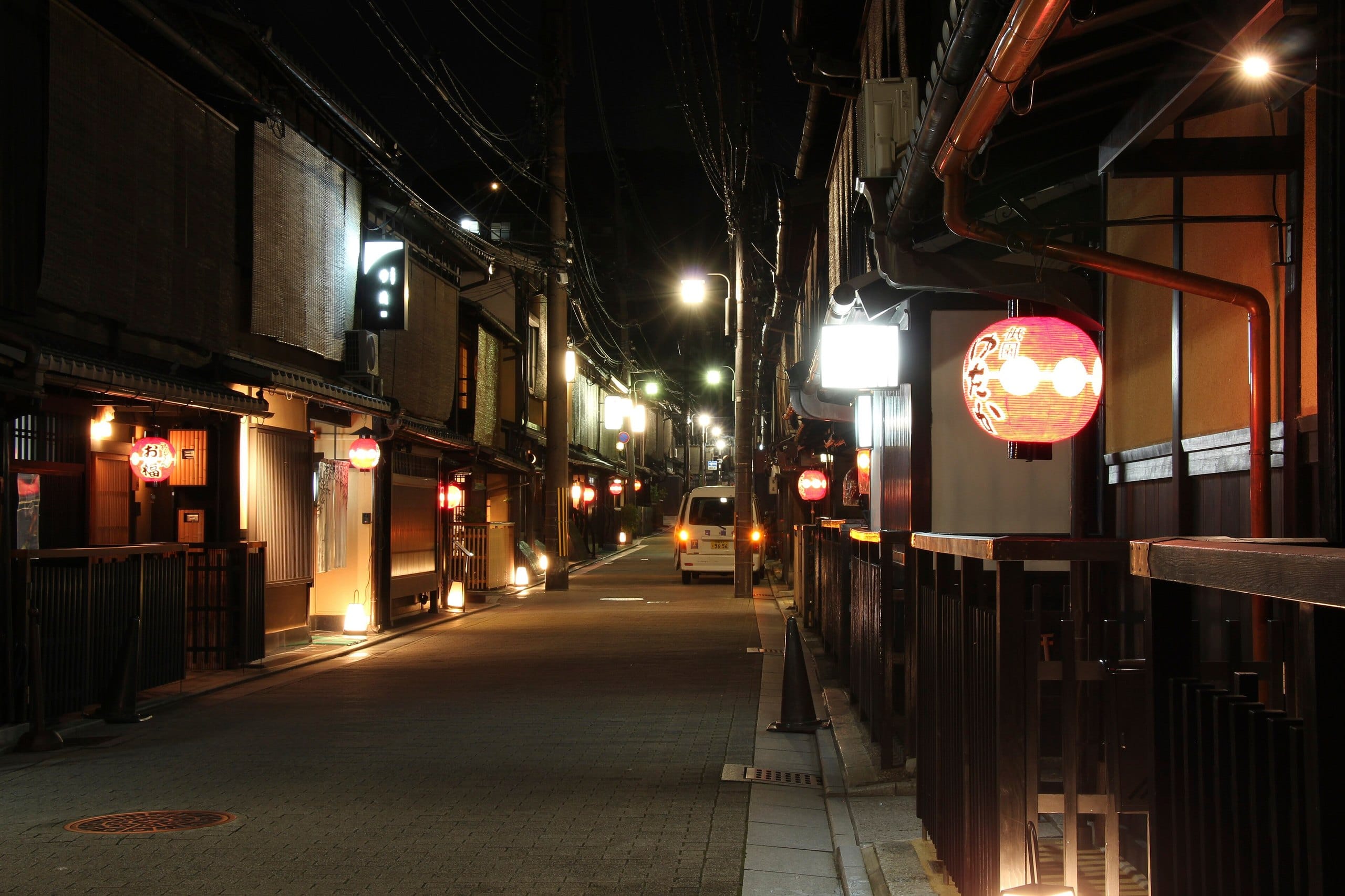 A quiet Gion street at night lit by paper lanterns and old wooden facades