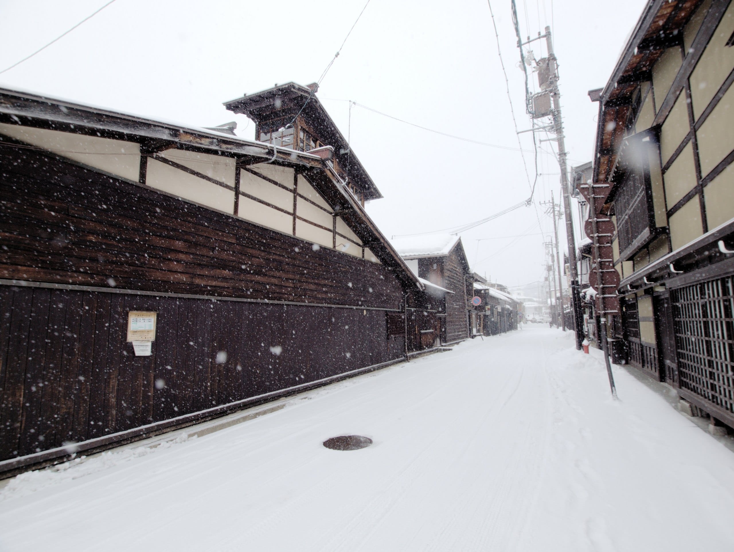 Dark wooden merchant houses along a snowy street in Takayama