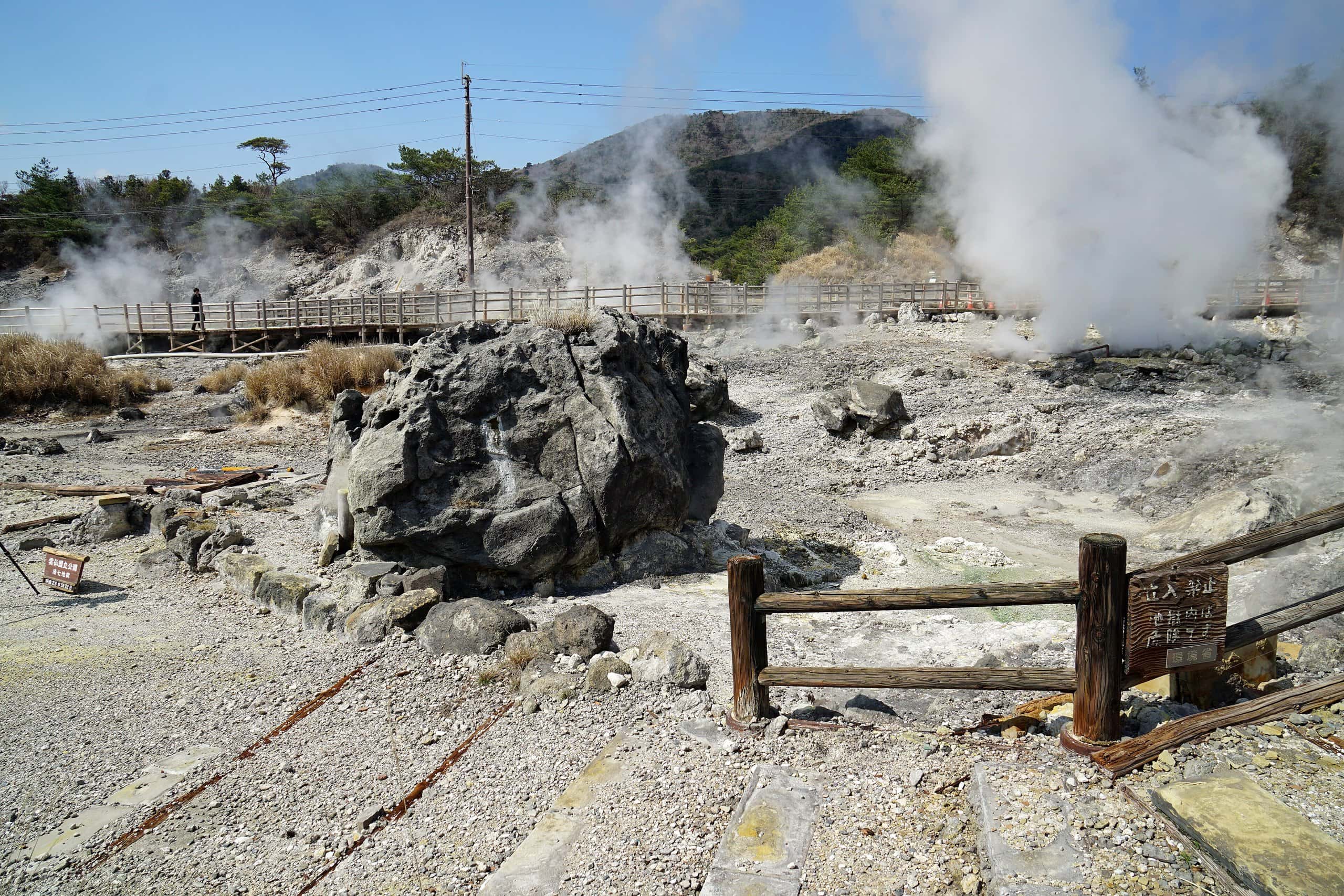 Steam vents rising behind a large boulder in the geothermal field