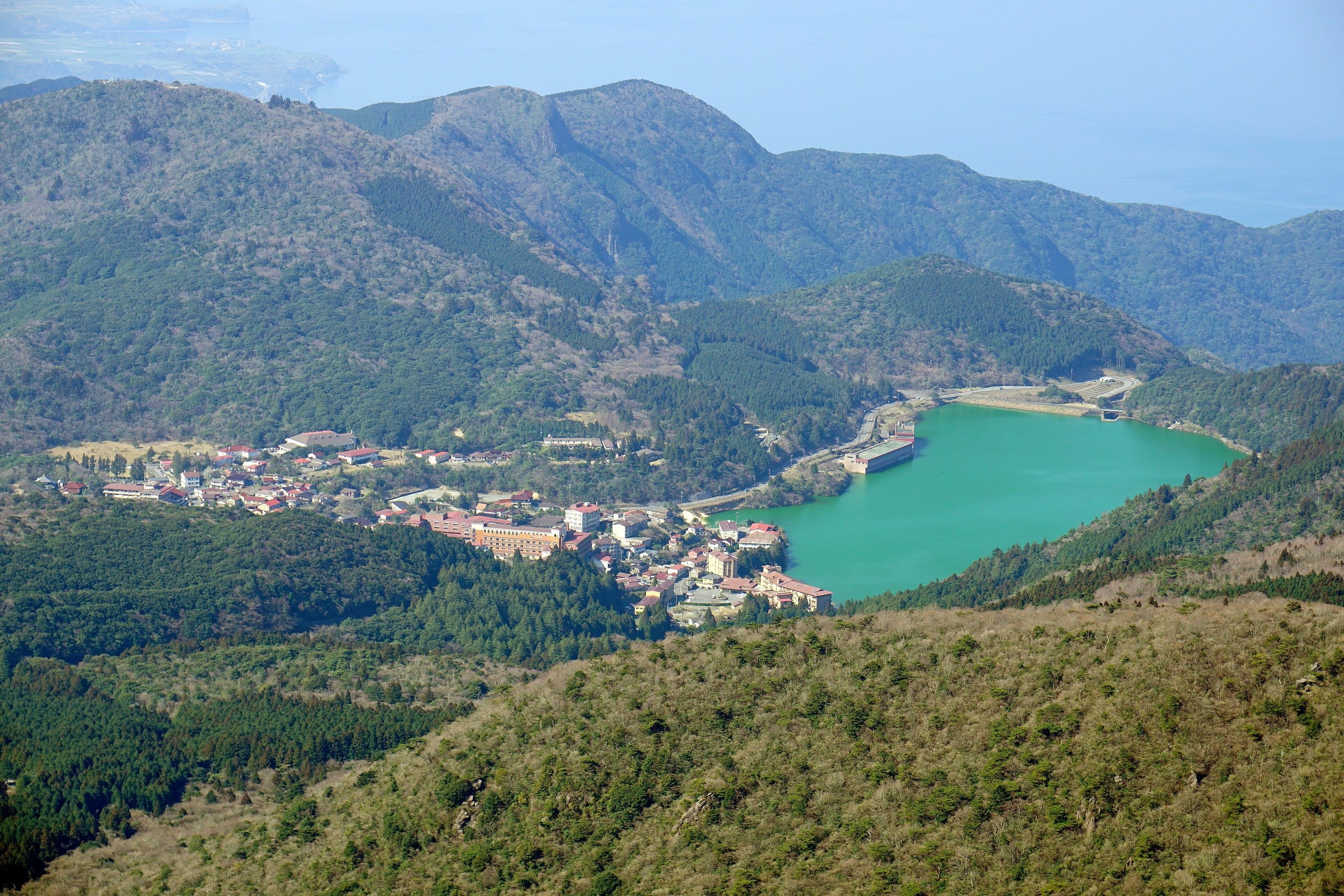 Unzen Onsen town and a turquoise lake seen from the mountains above