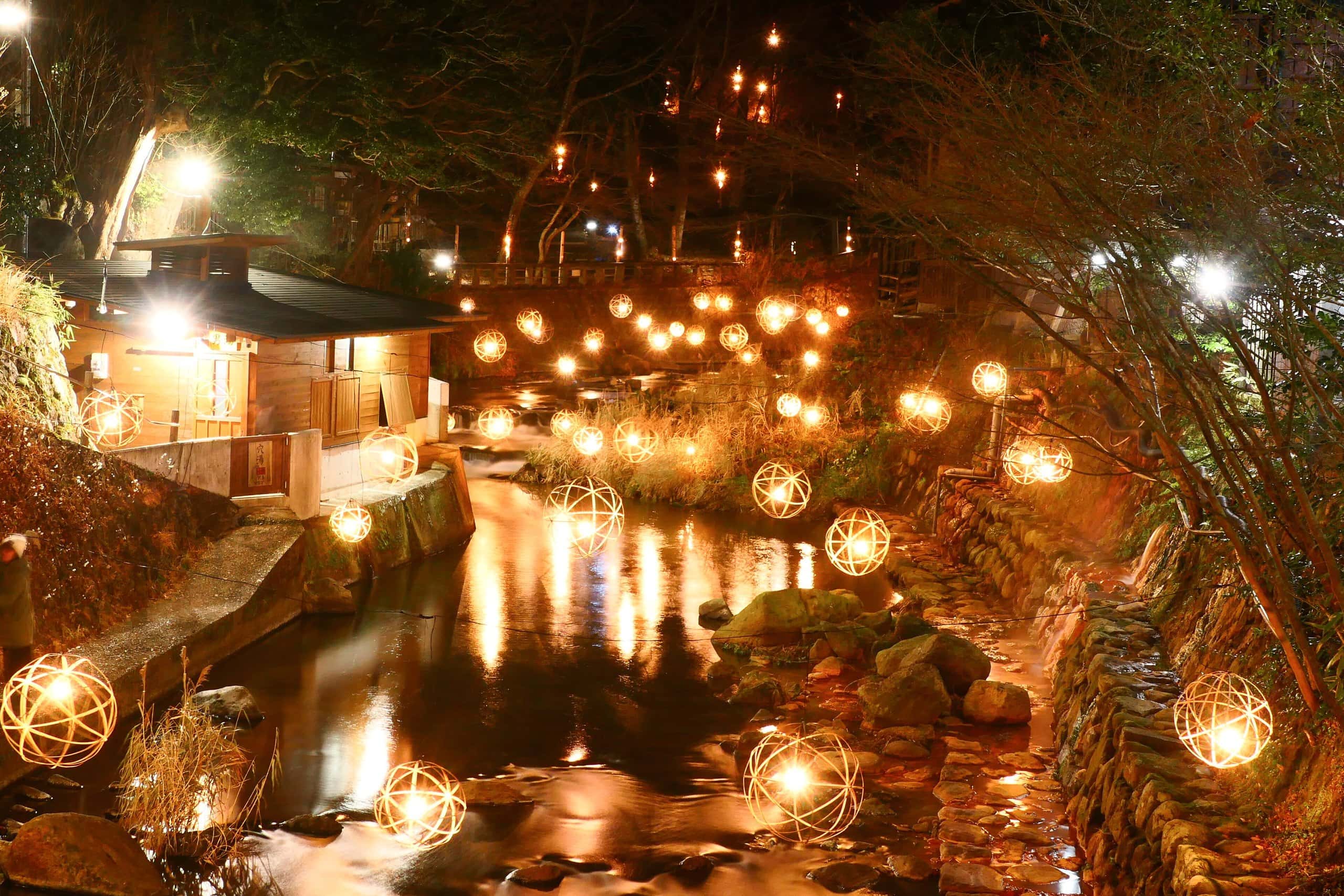 Bamboo lantern balls glowing along a stream in Kurokawa Onsen at night