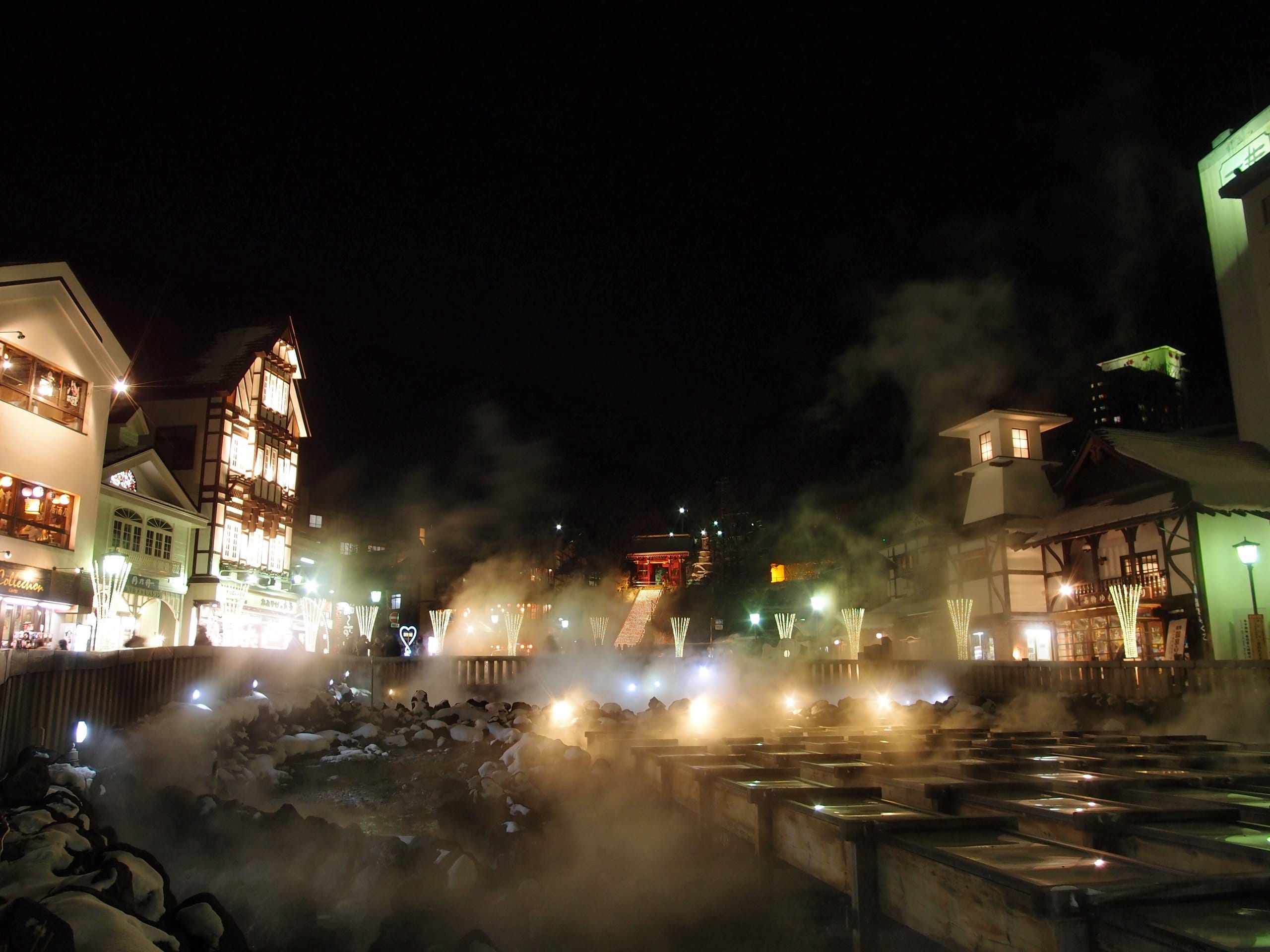 Steam rising from the Yubatake hot-spring field in Kusatsu at night, lit by warm lamps