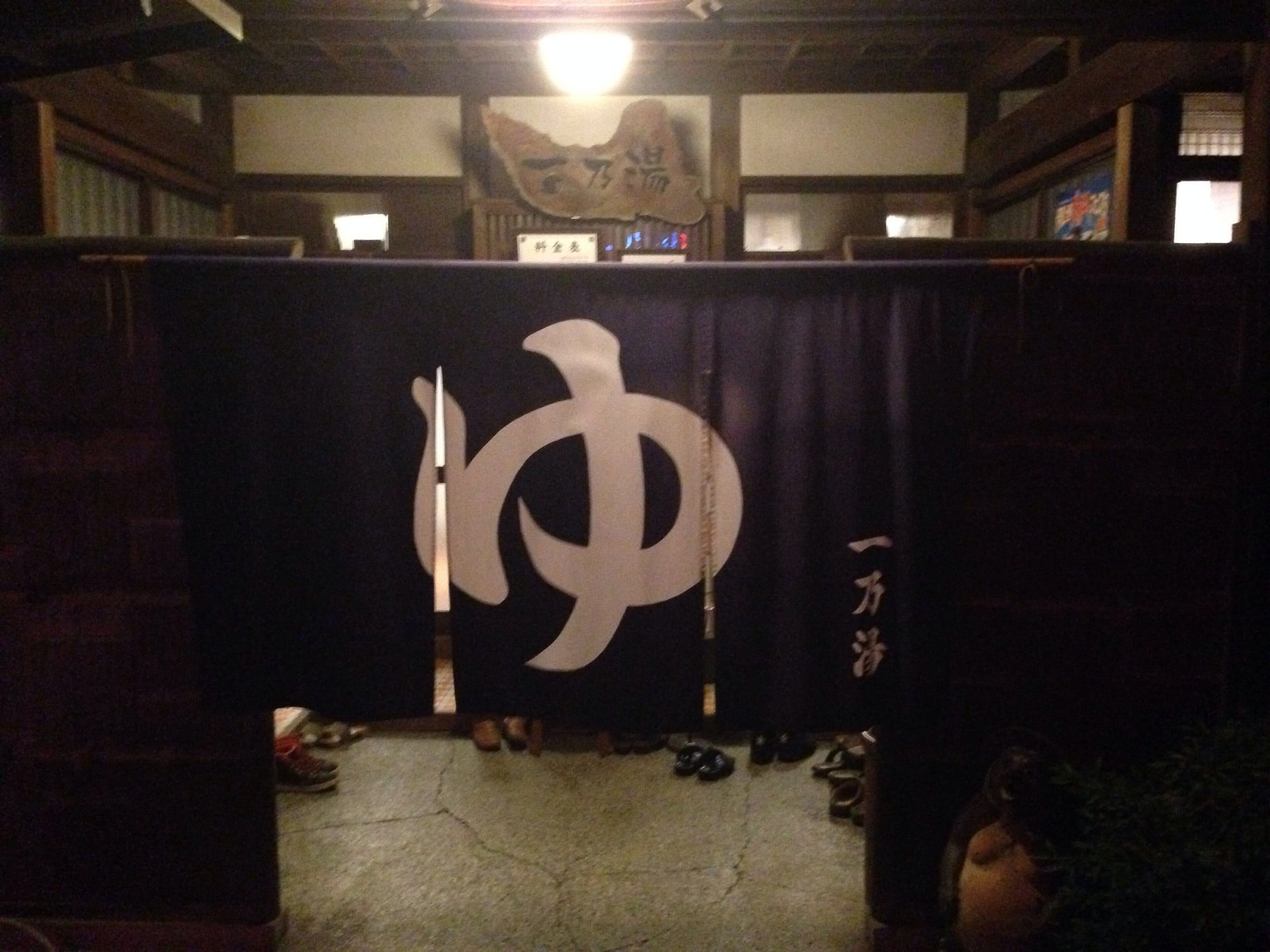 Dark indigo bath curtain with the hiragana for hot water, lit at night