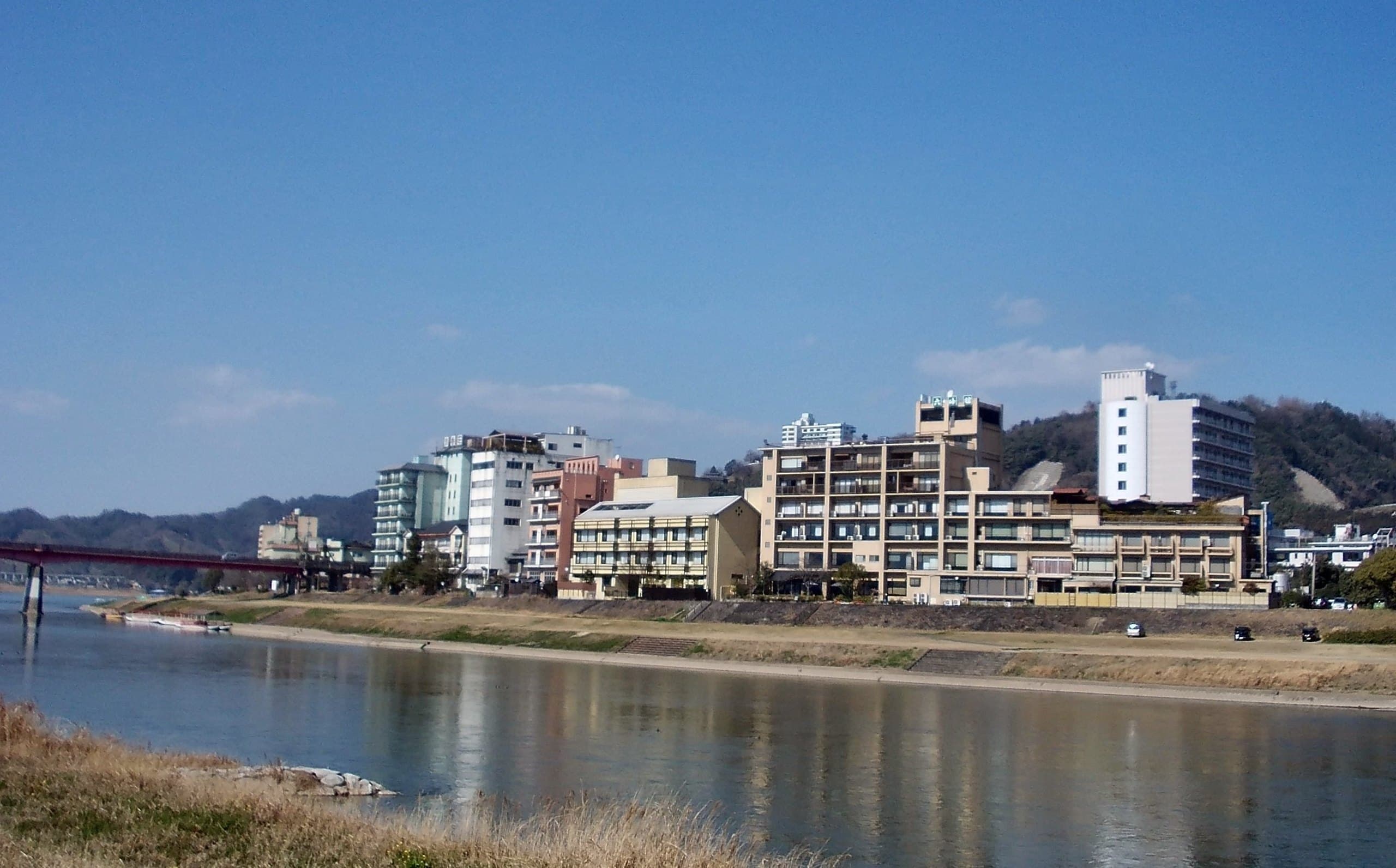 Hotels and inns of Harazuru Onsen reflected in the Chikugo River under a blue sky
