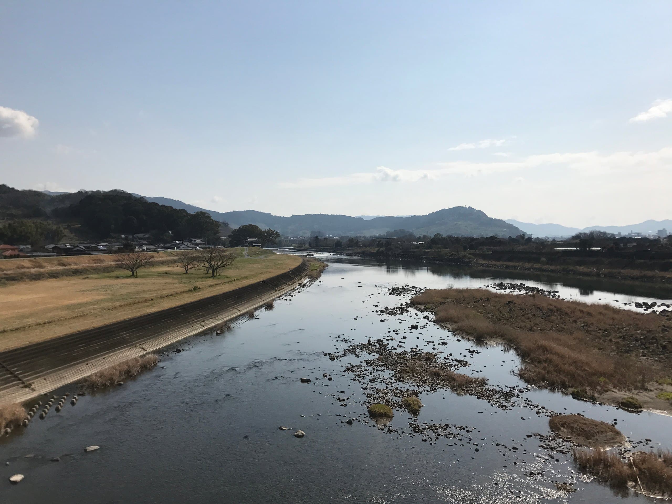 The broad, shallow Chikugo River with grassy banks and hills in the distance