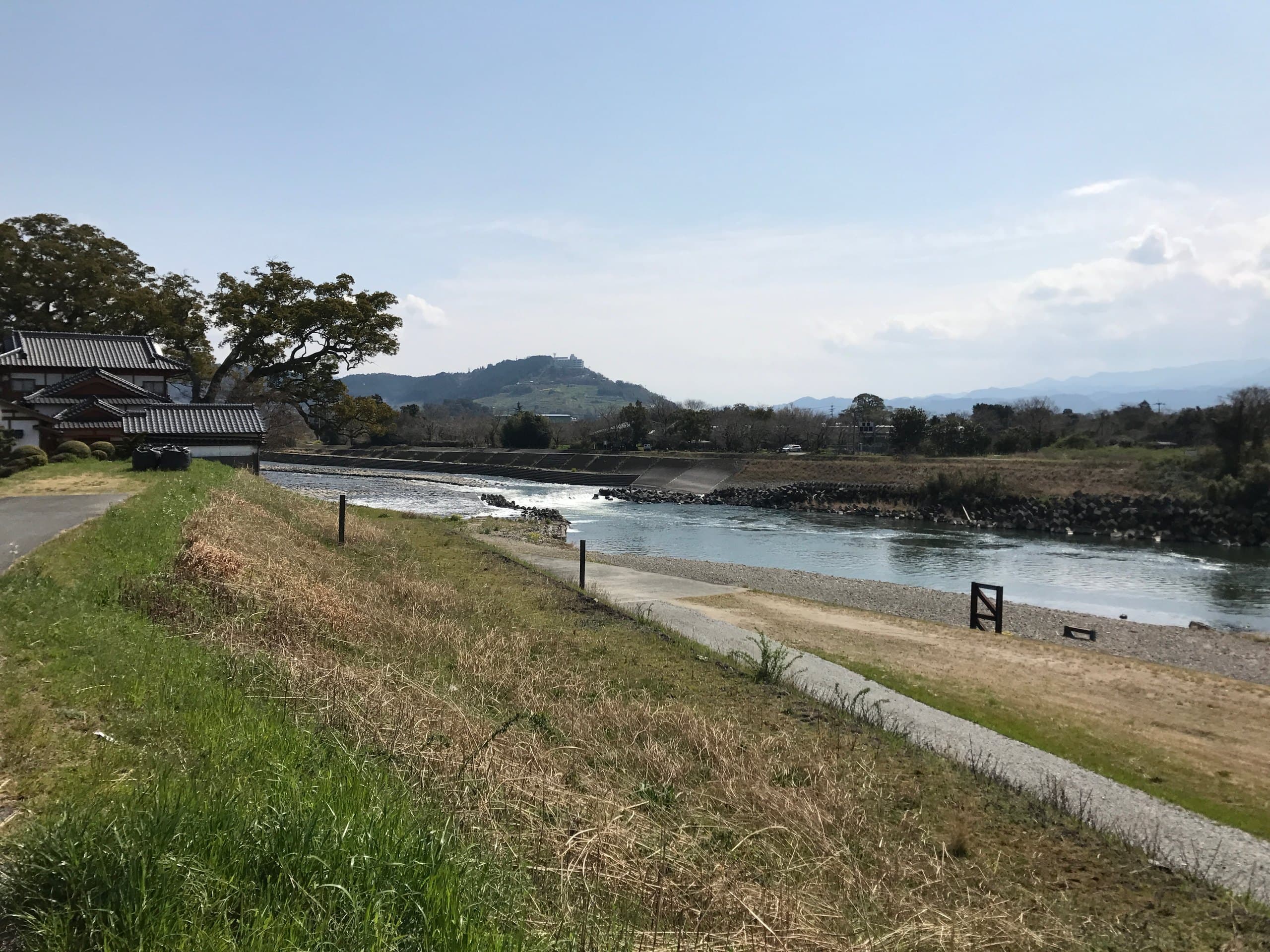 River water spilling over the long stone Yamada Weir on the Chikugo River, seen from the grassy embankment