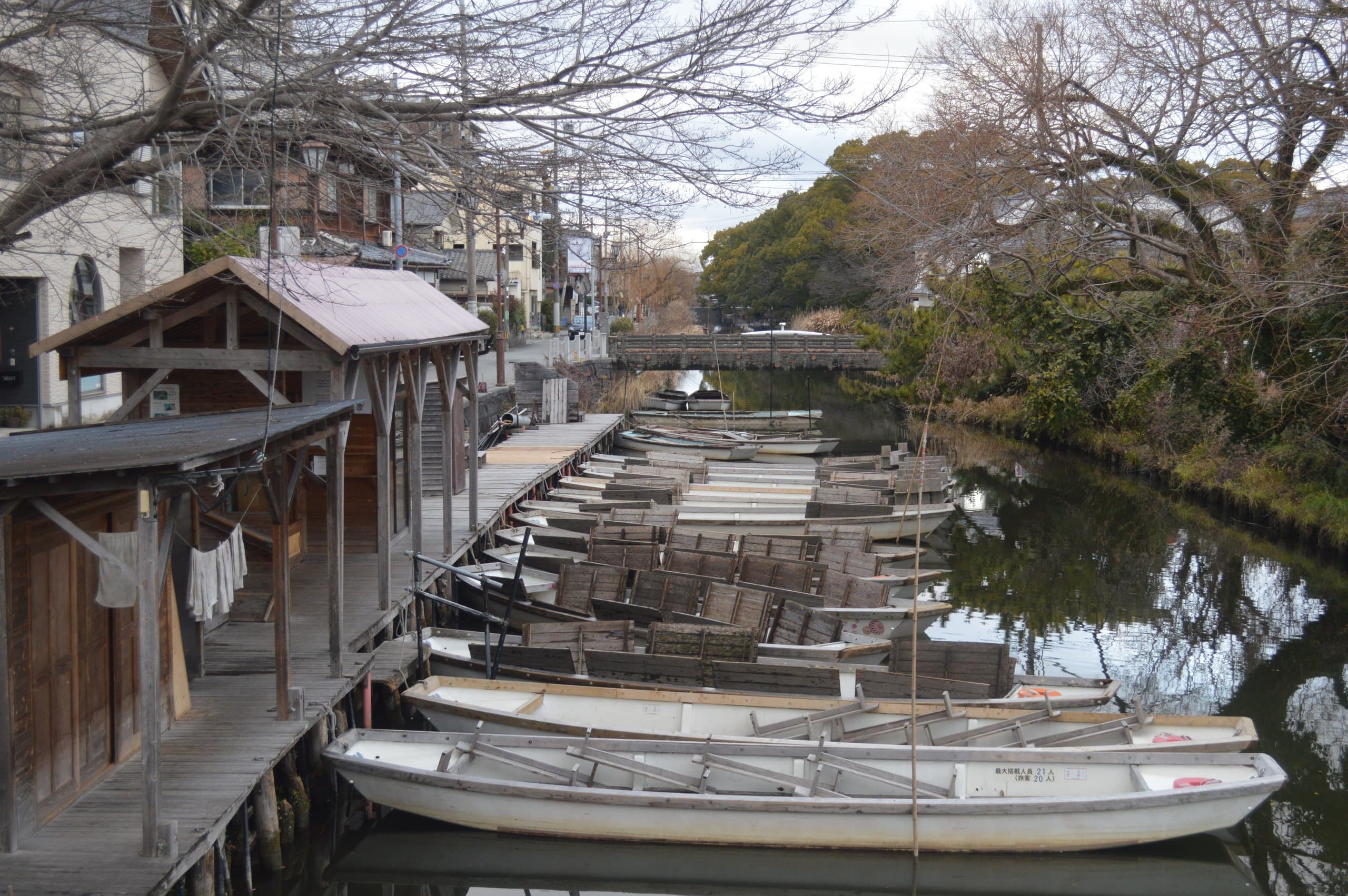 Rows of empty wooden punts moored at a boat landing on a canal in Yanagawa