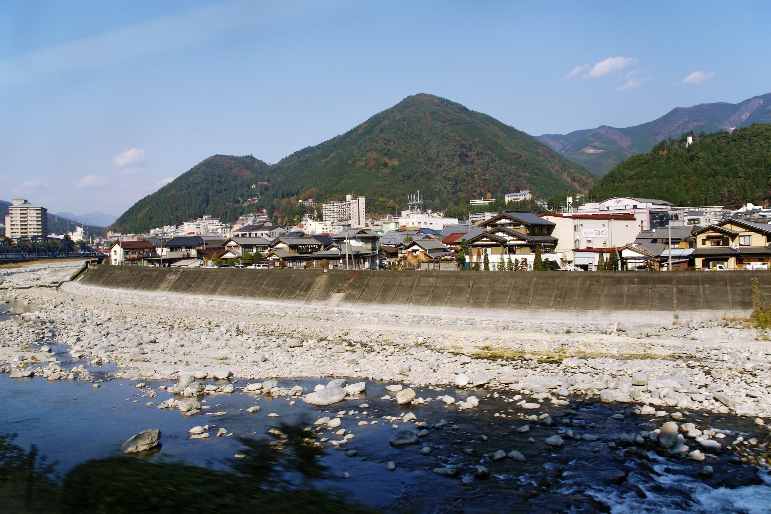 Gero Onsen's houses and inns along the wide stony bed of the Hida River, with wooded hills behind